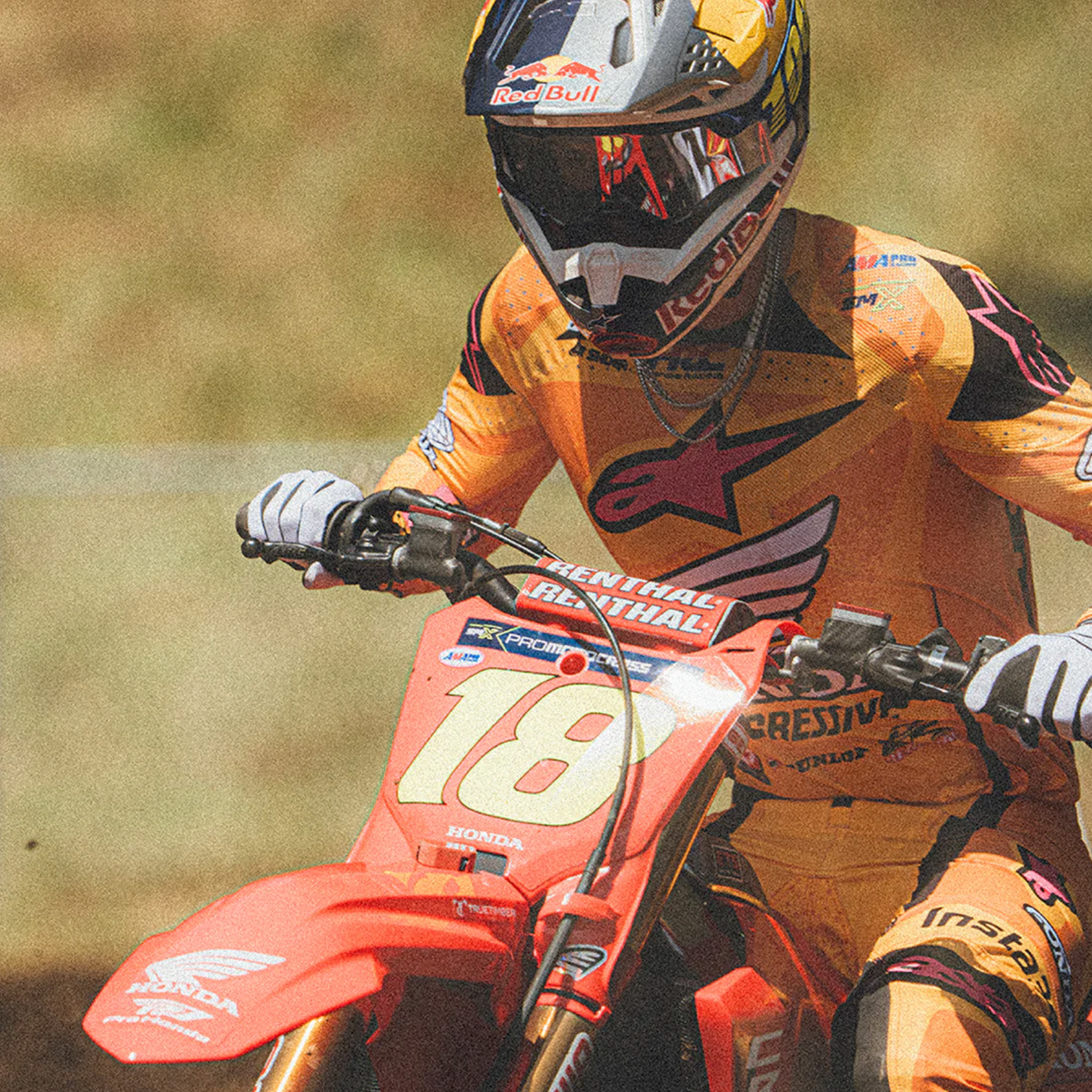 Motorcycle racer in action with a dirt bike, wearing a helmet and racing suit.