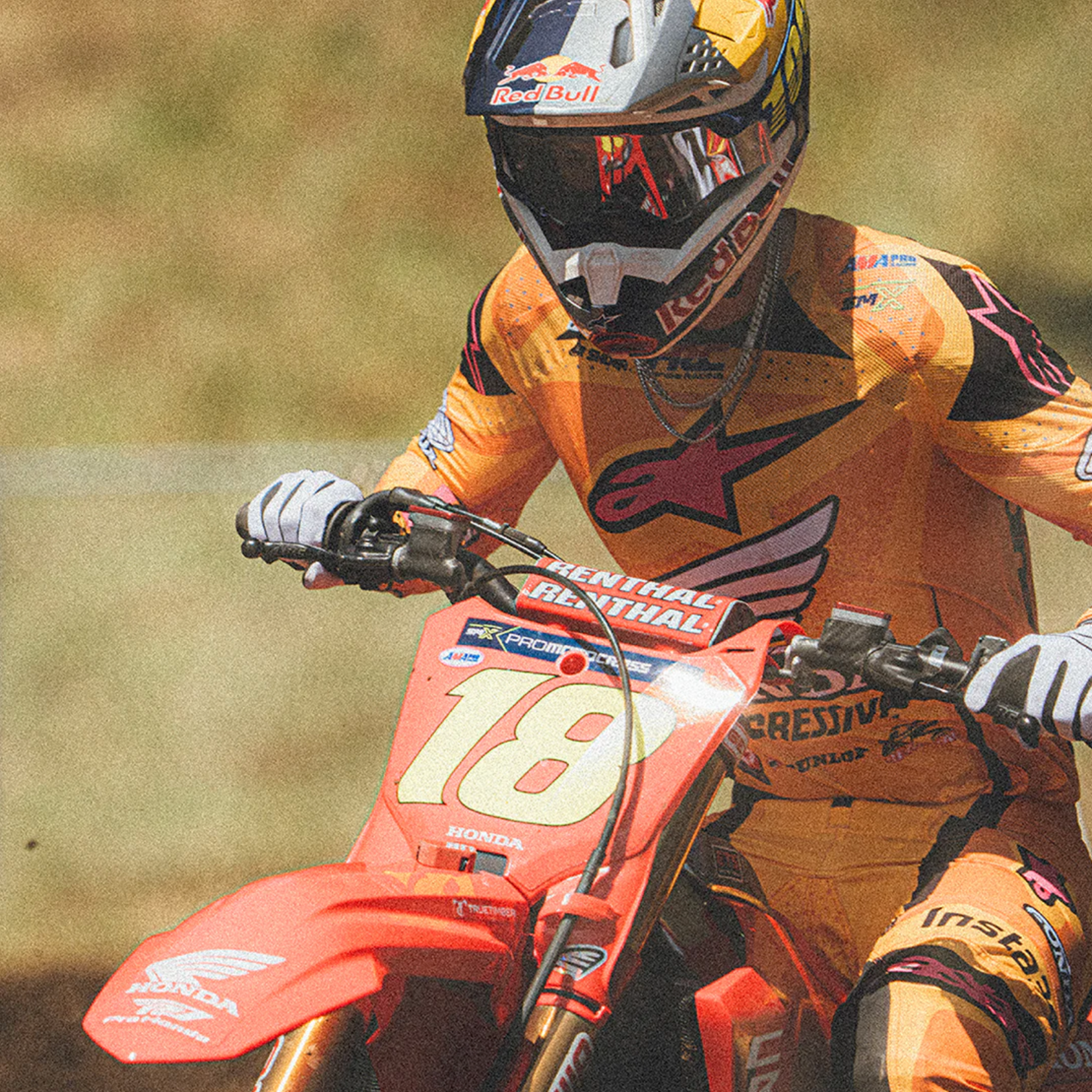 Motorcycle racer in action with a dirt bike, wearing a helmet and racing suit.
