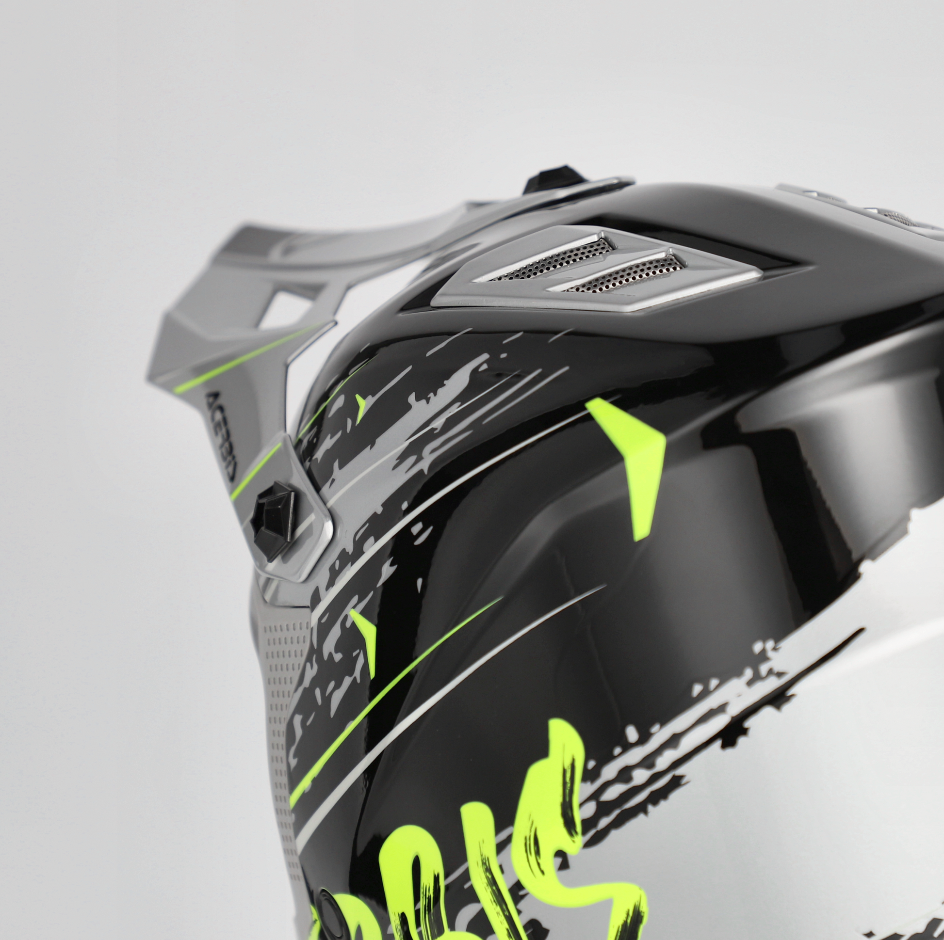 Close-up of a motorcycle helmet with black, gray, and green design on a light gray background