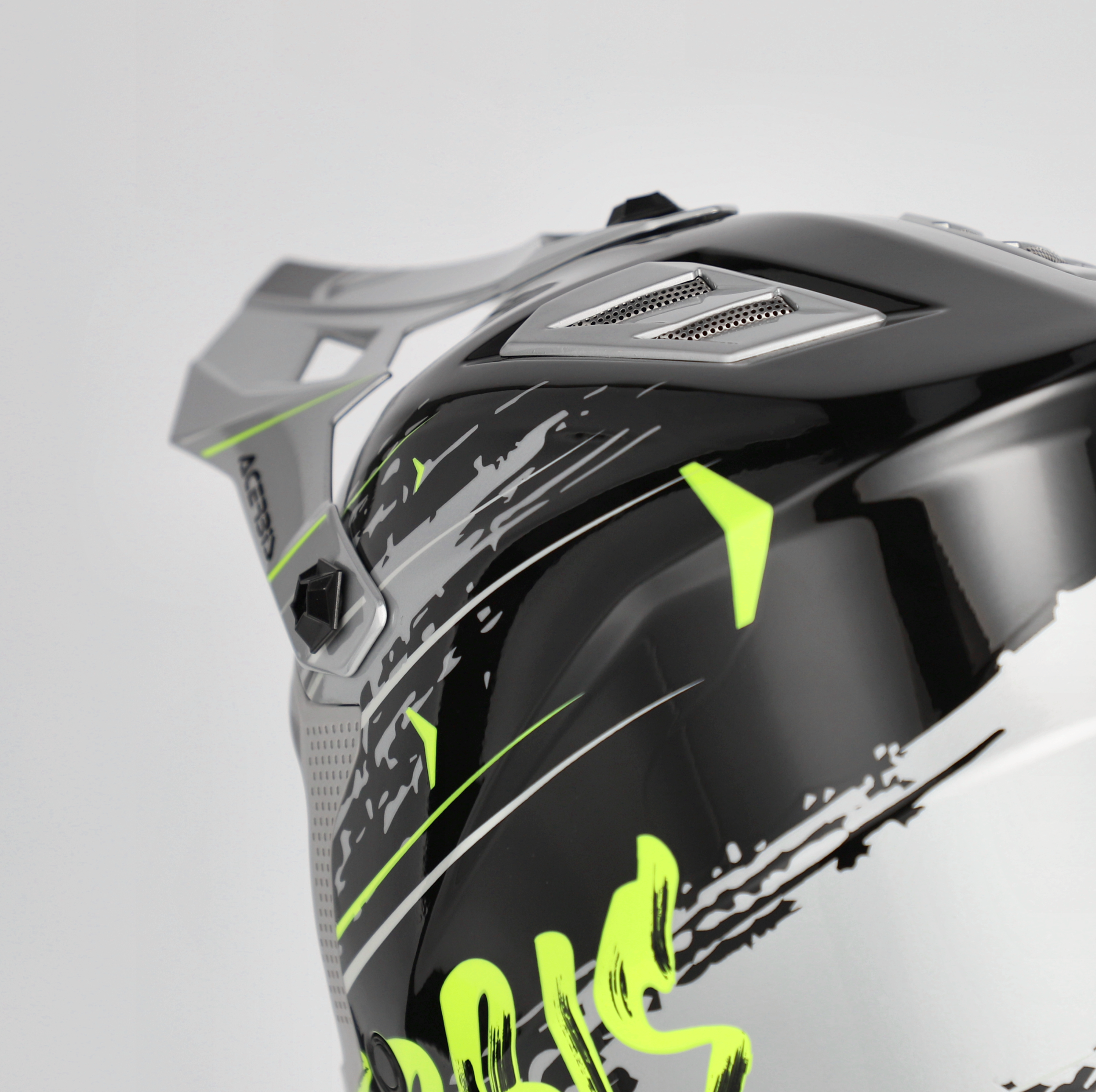 Close-up of a motorcycle helmet with black, gray, and green design on a light gray background