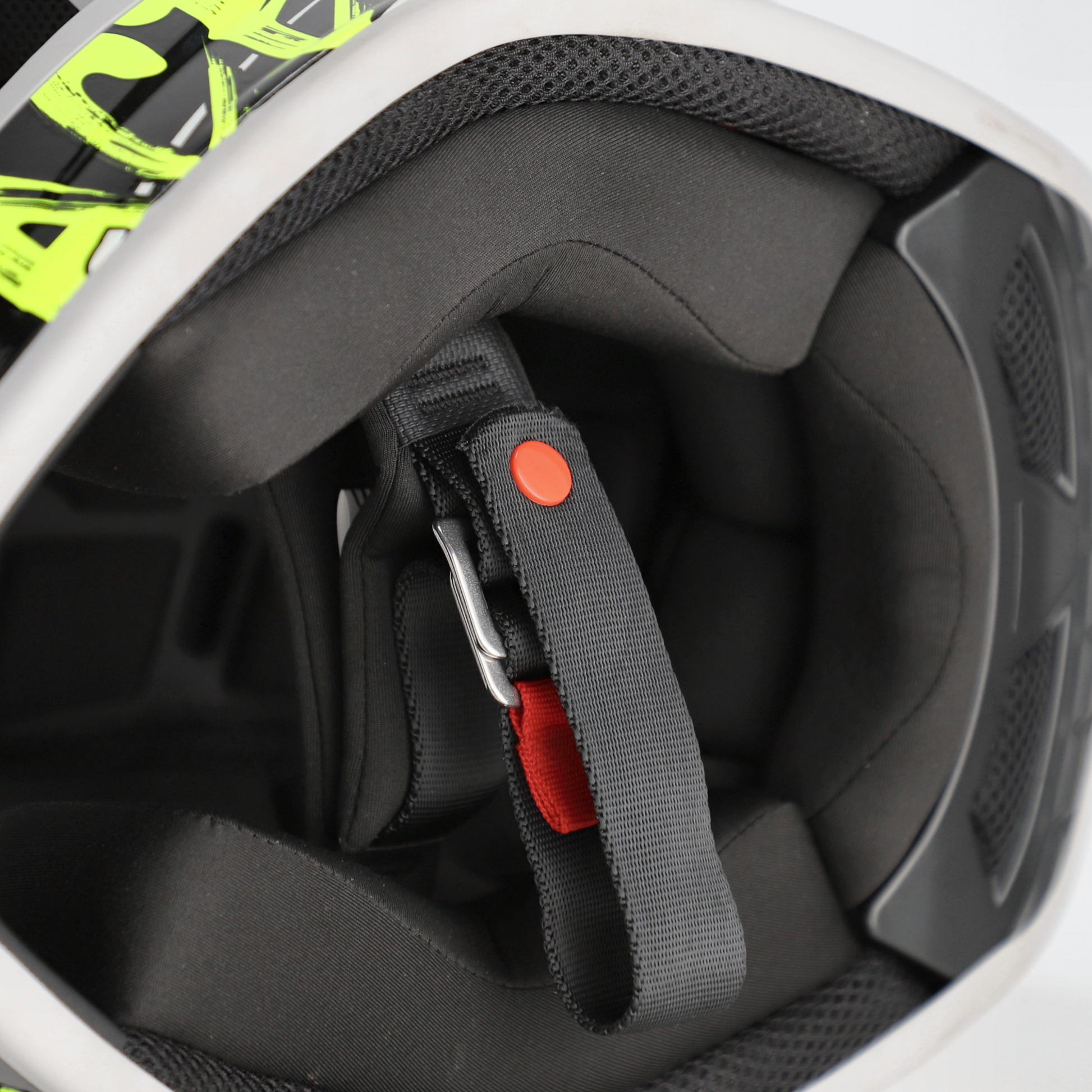 Close-up of a helmet interior with a chin strap and red buckle.