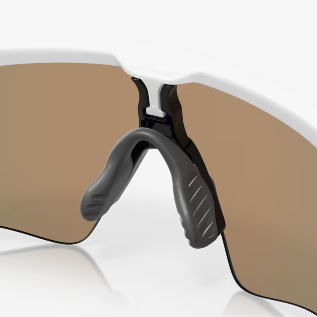 Close-up of a white wraparound sports sunglasses with a brown-tinted lens and black nose pads, shown on a clean white background.