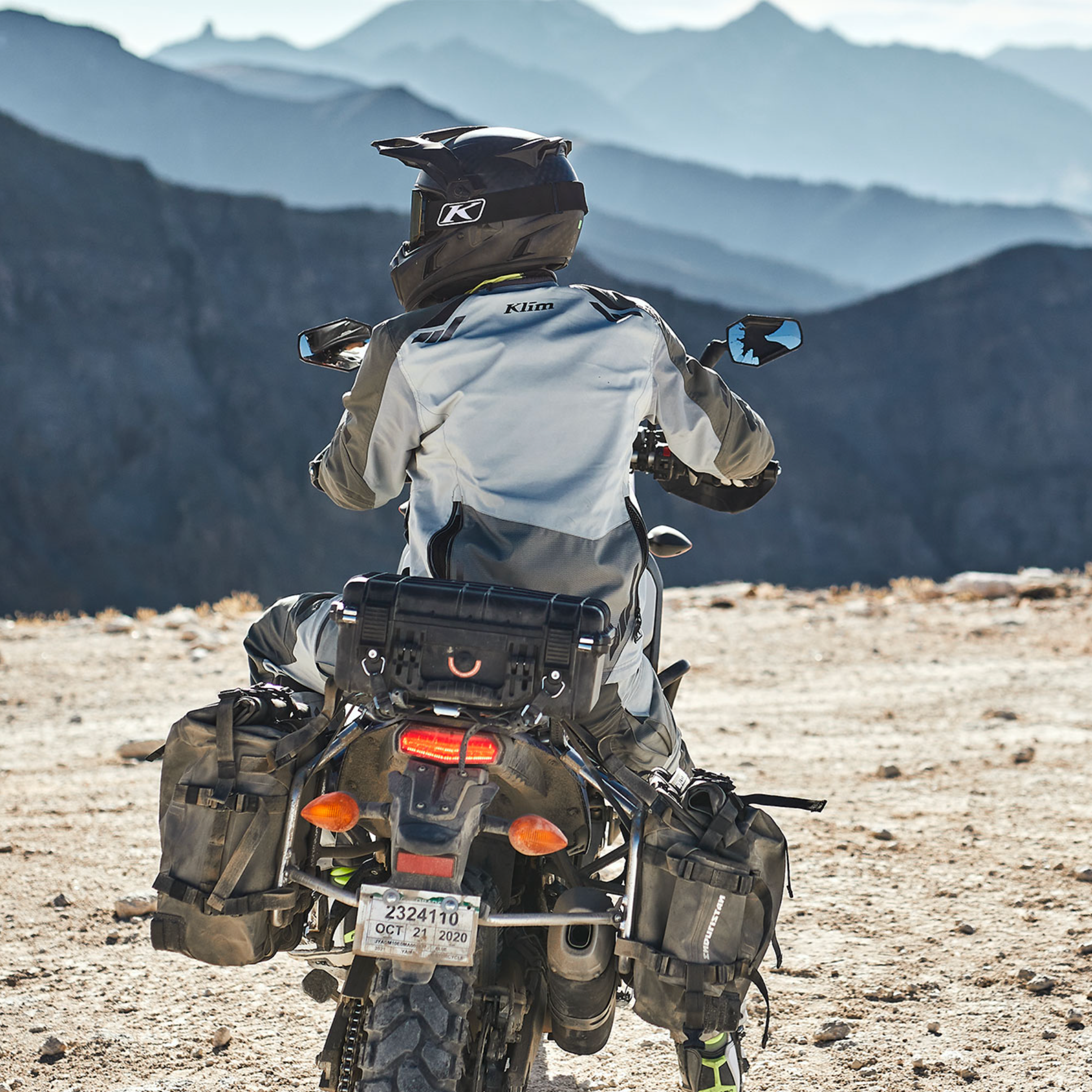 Person riding a motorcycle in a desert landscape with mountains in the background