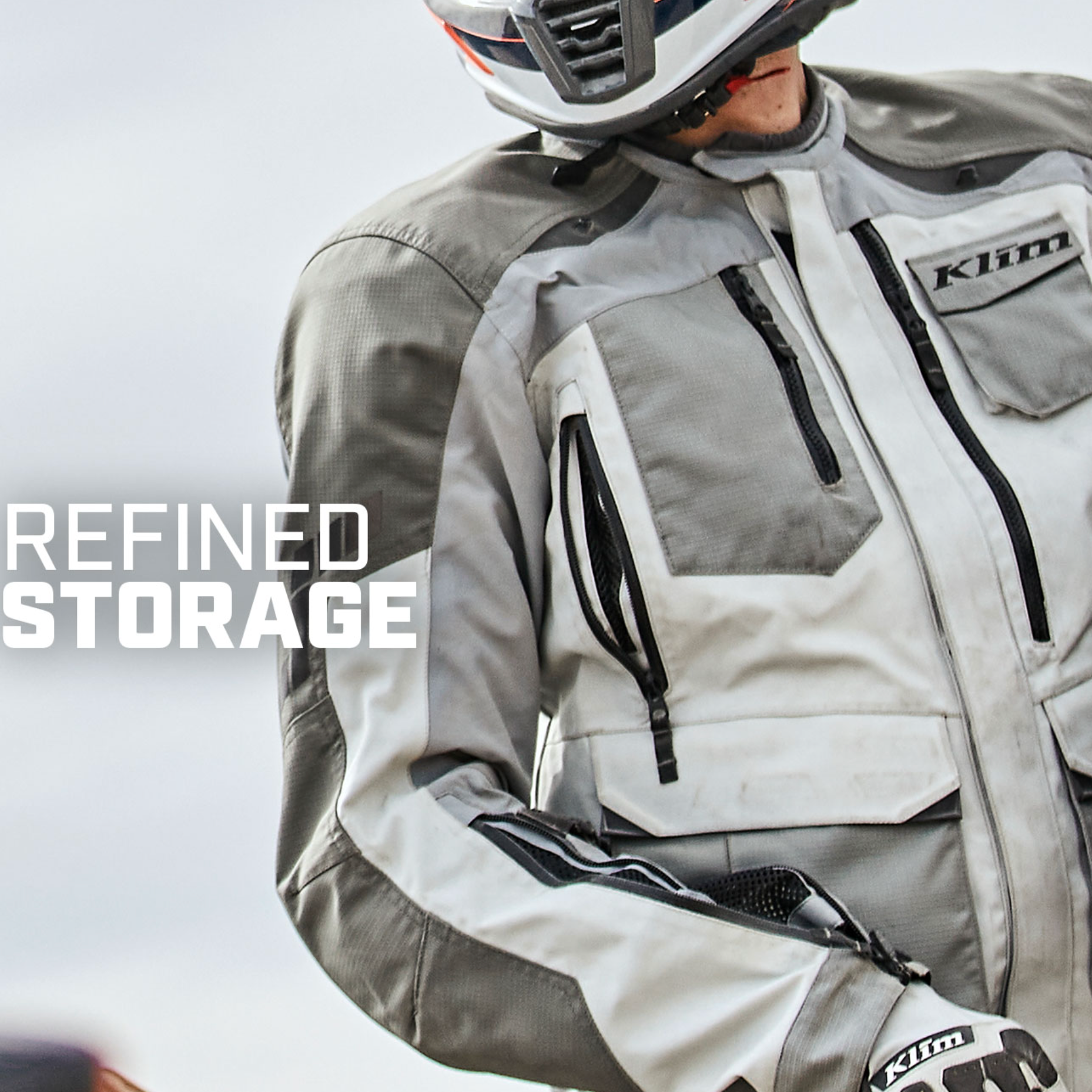 Person wearing a Klim motorcycle jacket with storage compartments on a light background