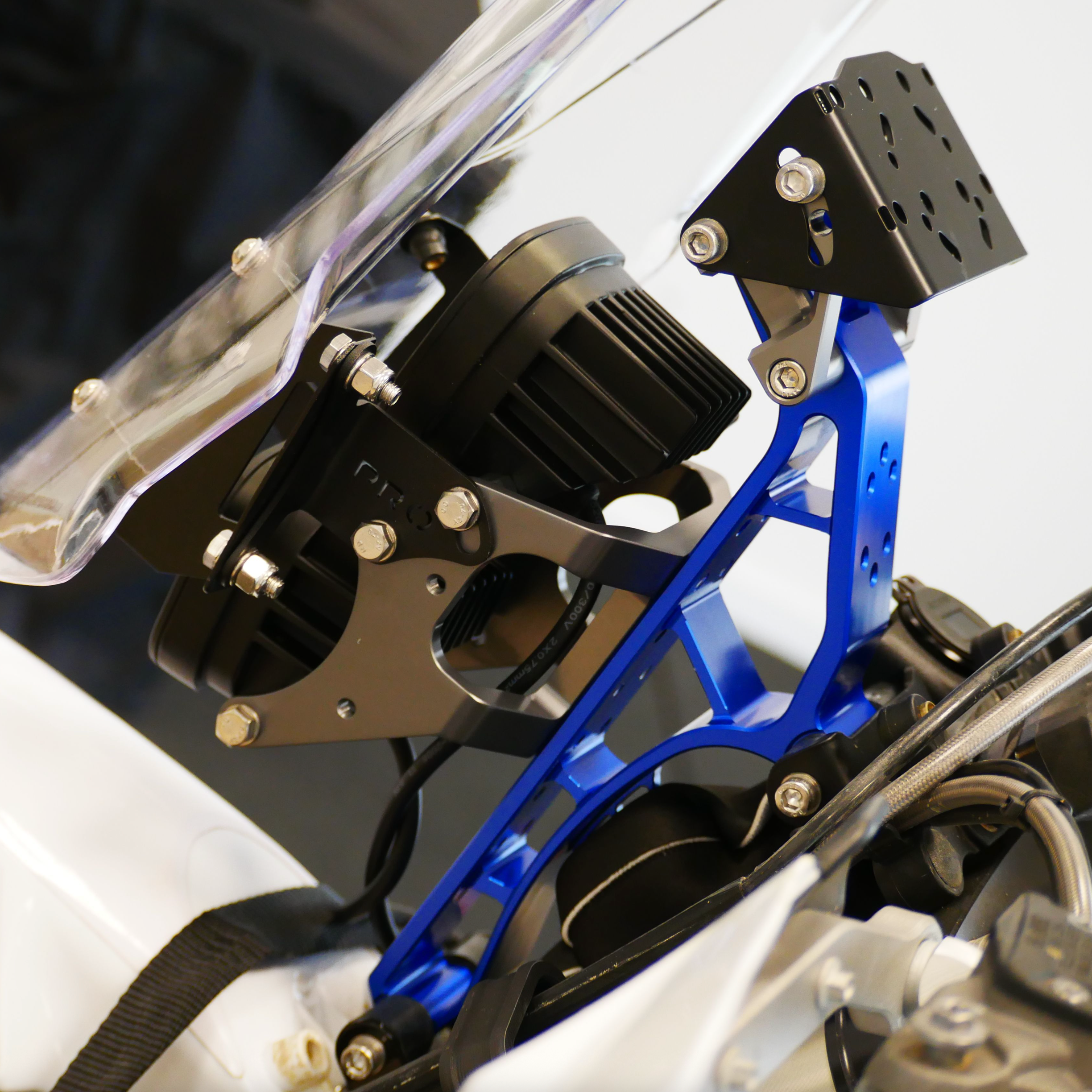 Close-up of a motorcycle's headlight assembly with blue metal bracket