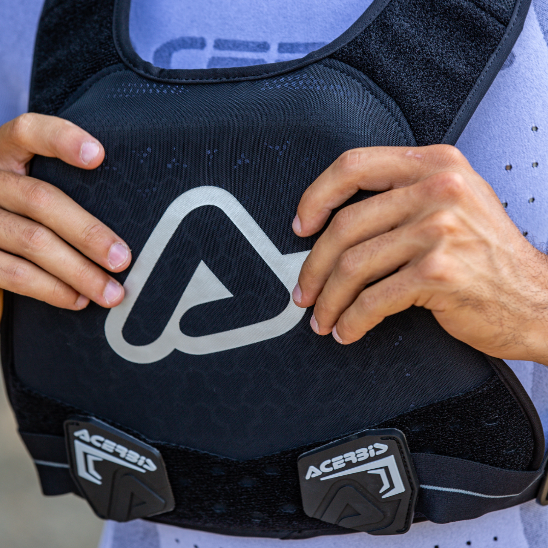 Person holding a black Acerbis protective vest with branding.