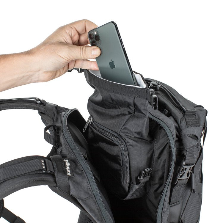 Person placing a smartphone into a compartment of a black backpack on a white background